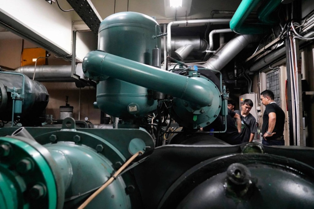 Technicians alongside large commercial refrigeration or HVAC equipment during recovery work in Indonesia